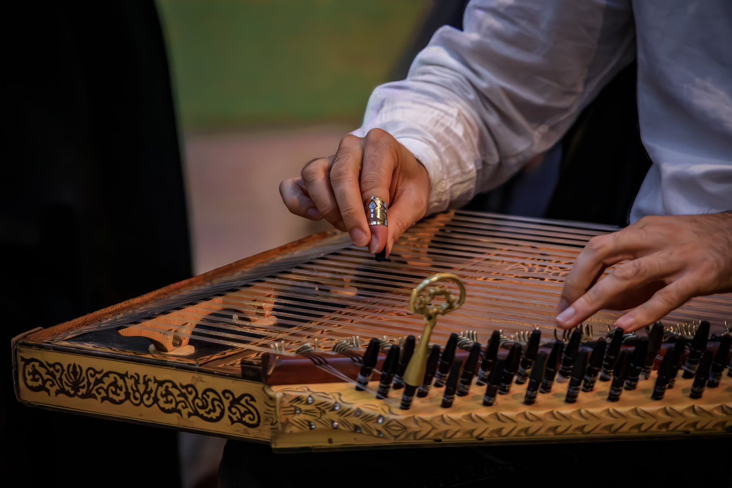 Close up of a musician's hands playing a traditional ornate Turkish Kanun, a Middle Eastern stringed instrument using metal picks in Istanbul, Turkey